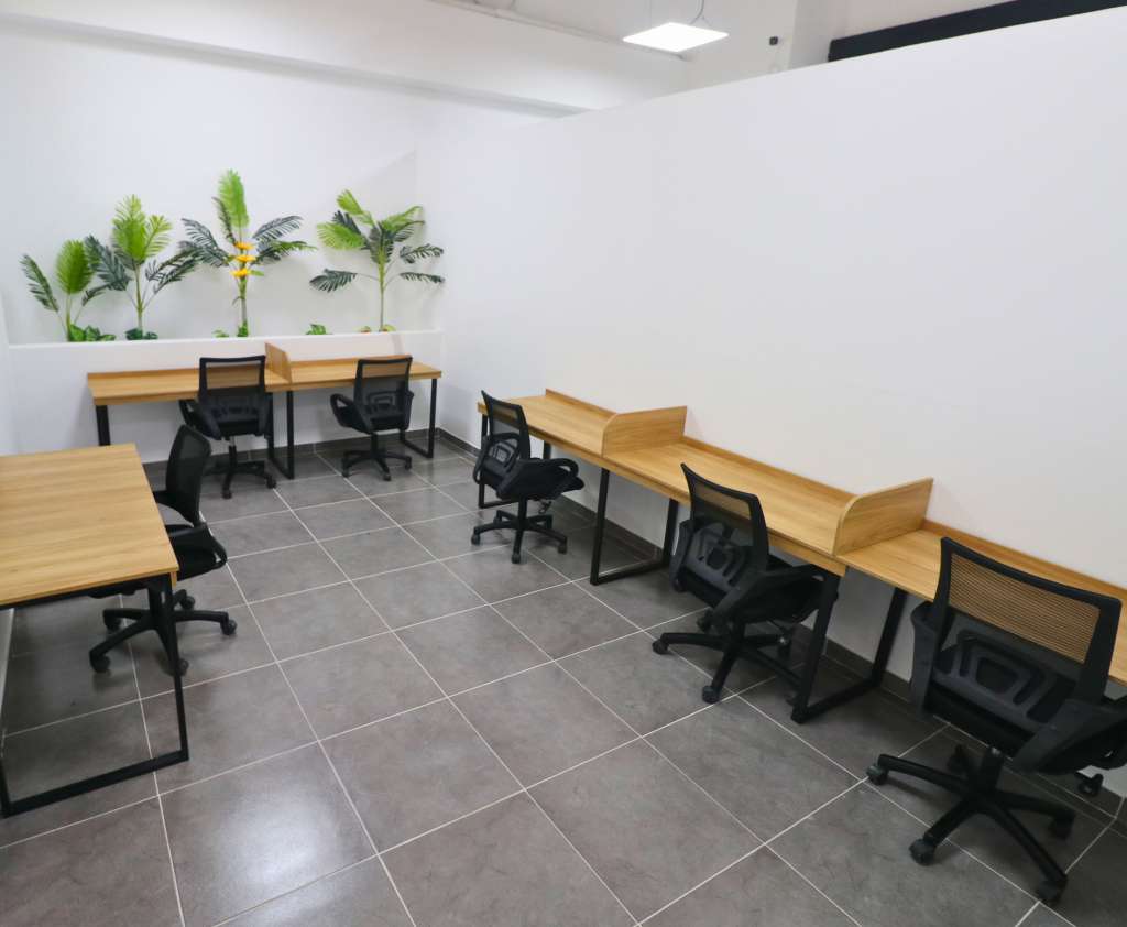 Oficina de 6 personas con escritorios, sillas, y aire.